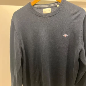 Mörkblå stickad tröja från GANT - Mörkblå stickad tröja från GANT i nyskick, passar alla med strl M, skönt material och skön passform!