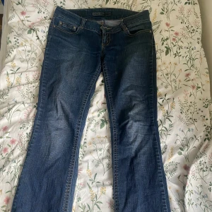 Blå bootcut jeans från ONLY - Säljer ett par lågmidjade bootcut jeans från ONLY med snygga kontrastsömmar och femficksmodell. Jeansen har normal passform och är tillverkade i jeansmaterial. Perfekta för dig som gillar en tidlös look.