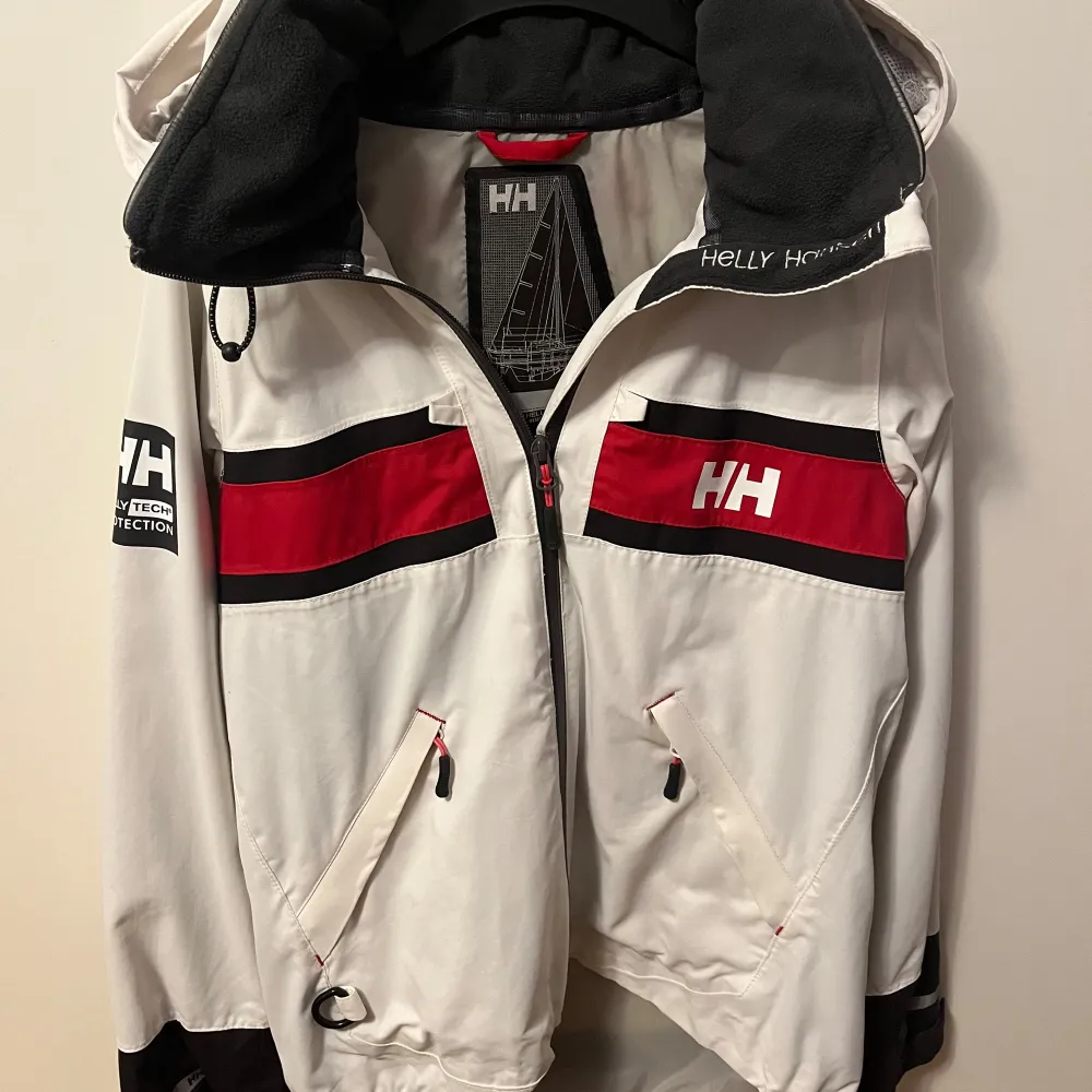 Säljer en riktigt schysst vit vindjacka från Helly Hansen, perfekt för blåsiga dagar! Säljer jackan pågrund av att den inte längre passar!. Takit.
