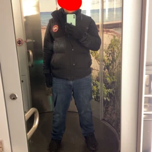 Svart pufferjacka med märke - Säljer en svart väst  med ett välkänt märke. Jackan har en dragkedja framtill. Perfekt för kyligare väder.