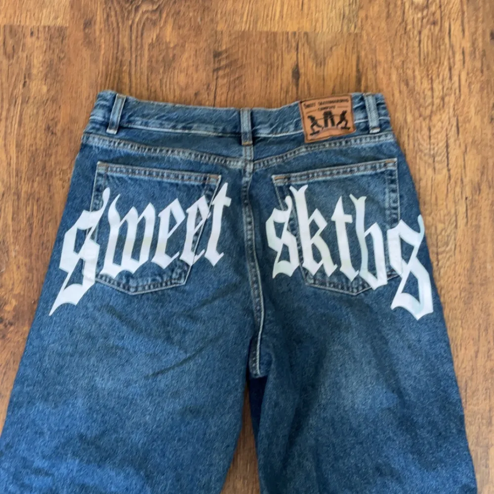 Säljer ett par blå jeans från Sweet SKTBS med coolt tryck på baksidan. De har en loose passform. Ny priset är 900kr. Ytterben - 100 cm Innerben - 73 cm Midja - 38 cm. Farkut & Housut.