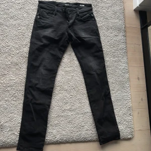 Svarta jeans från Replay - Snygga svarta jeans från Replay i modellen Anbass. De har en klassisk femficksdesign och en dragkedja. Perfekta för en stilren look.