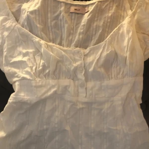 Vit blus från Nelly - Säljer en söt vit blus från Nelly med korta puffärmar och knappar framtill. Säljer den då den inte kom till någon användning! Har aldrig använts, är i ny skick men lappen finns inte kvar😉💞 köpt för 349😌