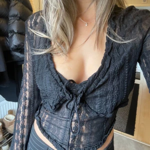 Svart spetsblus med knytning - Säljer e  svart spets linne med tillhörande spets kofta. Från tiger mist. Storlek L men liten i storleken.