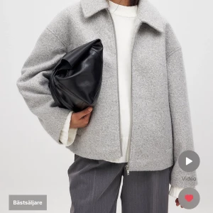 Grå ulljacka med dragkedja - Snygg och stilren grå jacka i ull med dragkedja framtill. Jackan har en klassisk krage och långa ärmar, perfekt för kyligare dagar. Den har en loose passform som ger en avslappnad look. Nypris 899kr