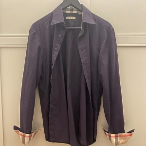 Burberry skjorta - Säljer en Burberry skjorta i mycket bra skick. Den är en storlek M. Färgen är en lila aktig färg men i en blåare nyans. För mer detaljer och mer bilder skriv gärna till mig! Pris går att diskutera, så kom med bud!