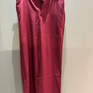 Vinröda kostymbyxor från Black Colour - Snygga vinröda kostymbyxor från Black Colour i en elegant och skräddarsydd stil. Byxorna har en midwaist design och är perfekta för en stilren look. De är tillverkade i ett mjukt och bekvämt material som ger en lyxig känsla.