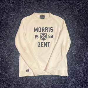 Vit tröja från Morris Gents - Säljer en stilren vit tröja från Morris Gents med tryck framtill. Tröjan har långa ärmar och ribbade muddar vid ärmslut och nederkant. Perfekt för en klassisk look. Det finns en missfärgning i kragen men syns inte när den sitter på, hör av er vid minsta fundering🙌