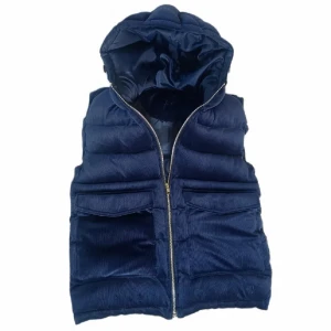 Mörkblå quiltad dunväst - Snygg mörkblå dunväst med quiltad design och dragkedja framtill. Västen har en praktisk huva och två stora fickor med lock. Perfekt för kyligare dagar. Västen är från vendiera och säljs inte längre, hör av dig om du undrar något! 