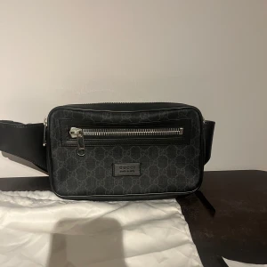 Svart axelväska från Gucci - Magväska från Gucci, köpt på illum i Köpenhamn. Bra skick förutom att ena blixtlåset är borta men inget som påverkar