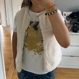 Vit pälsväst - Säljer en stilren vit pälsväst som är perfekt för att hålla värmen. Västen har en mjuk och fluffig yta och är utan knäppning, vilket ger en öppen och avslappnad look. Passar bra över en t-shirt eller tröja för en trendig outfit. Storlek 140 men passar mig som oftast bär S. Alla bilder är mina egna, aldrig använd! Pris kan diskuteras 