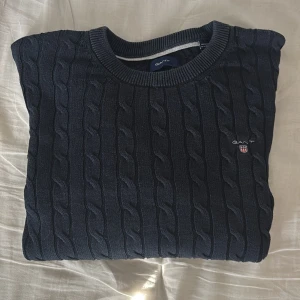 Svart kabelstickad tröja från GANT - Tja! Säljer denna snygga kabelstickad tröja från gant med en broderad GANT logga på bröstet, som passar perfekt under kyligare väder. Storleken är för 13-14 år och passar längden 158-164. Jag säljer tröjan på grund av att den är lite för liten för mig. Priset kan diskuteras.