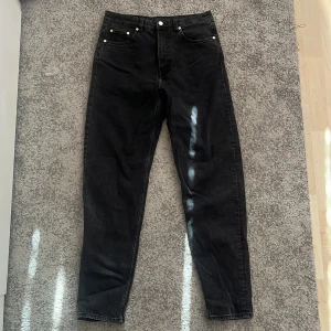Svarta jeans från Weekday - Säljer ett par svarta jeans från Weekday i modellen Lash. De har en hög midja och en dragkedja framtill. Perfekta för en stilren look.