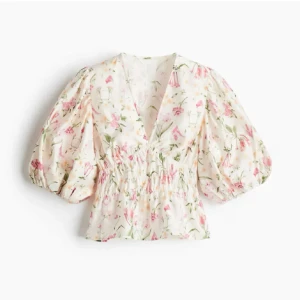 Blommig blus med puffärm och v-ringning - Supersöt blommig blus. Den har puffiga trekvartsärmar, smockad midja och djup v-ringning. Perfekt för dig som vill ha något luftigt och lätt till sommaren.