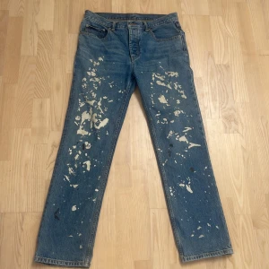 Helmut Lang Painter jeans re-edition  - Unika blå Painter Jeans från Helmut Lang med klassisk rak passform och coolt färgstänksmönster över hela byxorna. Tillverkade i robust denim av bomull, perfekt för dig som gillar statement-plagg med vintagekänsla.