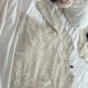 Beige spetsblus med lång ärm - Superfin beige blus från H&M i spets med vackra detaljer och lång ärm. Blusen har ett feminint mönster och snygg kant nertill och vid ärmslut.