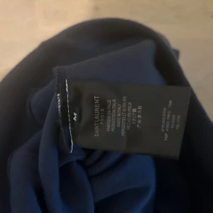 Saint Laurent marinblå hoodie - Tjena vi säljer nu våran mörkblåa ysl hoodie i storlek M. Hoodien passar däremot S då märket inte är trogna till sin storlek. Den är nästan i perfekt skick bortsett från att 1/2 av bokstaven I har flagnat bort. Tags medföljer men inte kvitto. Oroa dig inte just denna hoodie är känd för att inte kunna förfalskas då den har så komplexa detaljer. Priset är inte hugget i sten så släng ett skambud så kan du ta hem den idag mvh.