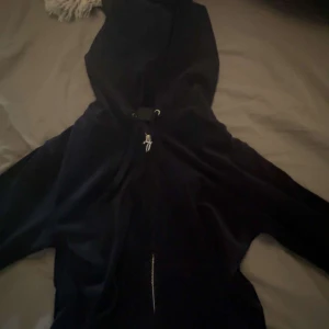 Svart hoodiejacka med dragkedja - Mysig svart hoodiejacka med dragkedja framtill och snörning i huvan. Perfekt för chill dagar och enkel att slänga på sig. Jackan har långa ärmar och en klassisk, avslappnad passform.