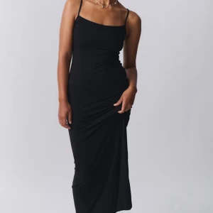 Svart långklänning med smala axelband - En stilren svart långklänning med smala axelband och figurnära passform. Soft touch kollektion från Gina tricot. Som ny och köpt för 300. Strectsig 