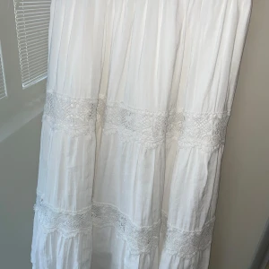 Vit långkjol köpt på marknad  - En somrig och gullig lång kjol i storlek XXS. Den har två broderi linjer och även en underkjol så att den inte är genomskinlig. Tyget längst utanpå ser och känns väldigt mycket som linne men är inte säker:) Har använt två ggr men har inga defekter alls💕