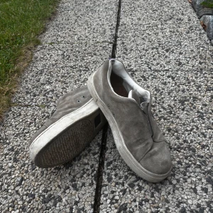 Grå mockasneakers med vit sula - Ett par snygga eytysdojor i storlek 45. Välanvända och säljer de så billigt då det är rätt slitna. På utsidan är det bra skick men det är ganska slitna bak i hälen. Priset är ej hugget i sten. Skriv för fler bilder eller vid intresse!☀️