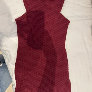 Vinröd kortklänning - Snygg vinröd kortklänning med coolt strukturerat tyg och asymmetrisk nederdel. Klänningen är ärmlös och har en figurnära passform som framhäver siluetten. Pris går att diskuteras!