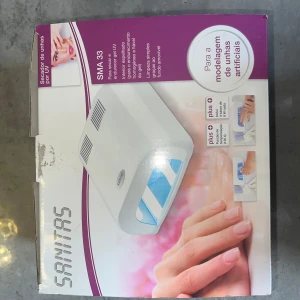 UV-nageltorkare Sanitas SMA 33 - UV-nageltorkare från Sanitas, modell SMA 33. Vit, kompakt design med speglad insida för jämn härdning av gelnaglar. Utrustad med 4 UV-lampor på 9W vardera (36W totalt), timerfunktion på 120 sekunder och uttagbar bottenplatta för enkel rengöring. Passar både fingrar och tår.