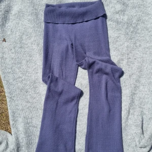 Lila stickade byxor från Gina Tricot - Mysiga lila stickade byxor från Gina Tricot med bred ribbad midja. Byxorna har en relaxed fit och är perfekta för chill dagar. Materialet är mjukt och stretchigt, vilket gör dem superbekväma att ha på sig.