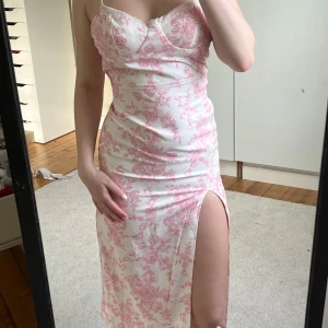 Vit och rosa blommig långklänning. Från shein! - Supersöt långklänning med smala axelband och blommigt rosa mönster på vit botten. Från shein så säljer billigt. Använd 1 gång på ett bröllop. För liten på mig på bilden. Strl xs