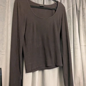 Brun långärmad topp från Gina Tricot - Mörkbrun långärmad topp från Gina Tricot med rund halsringning och smal passform. Tillverkad i mjuk bomullsmix, Ärmarna har en liten slits vid ärmslutet för en extra detalj. Använd sparsamt🫶🏻