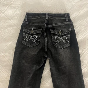 Svarta bootcut jeans med broderade fickor - Svarta jenas med bootcut-model och små rosett detaljer på fickorna 