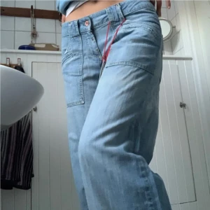 Ljusblå wide jeans med fickor - Säljer ett par ljusblå y2k jeans med breda ben och coola fickdetaljer framtill. Jeansen är uppsydda för att passa någon som är ~160-165 cm, men stygnen kan tas bort så att de blir ca 10 cm längre. 29” i midjan. (Lånade bilder, köpte dom här på plick för ~500kr, men bytt stil)