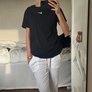 Svart Nike t-shirt  - Svart t-shirt från Nike med klassisk vit swoosh-logga på bröstet. Modellen är loose fit och har rund halsringning och korta ärmar. Tillverkad i mjuk bomull. Den är i barnstorlek men som ni ser så är den relativt stor på mig som vanligtvis har xs 💕