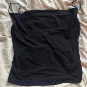 Svart linnetopp från Tempo Paris - En stilren svart linnetopp från Tempo Paris i storlek L. Toppen har tunna axelband och rak skärning, perfekt för en enkel och clean look. Materialet känns mjukt och följsamt mot huden. Passar dig som gillar minimalistisk stil och vill ha en topp som funkar till många outfits.