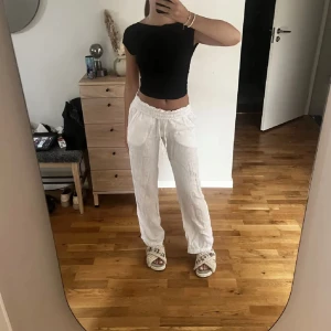 Vita linnebyxor Chelsea  - Säljer ett par vita linnebyxor med avslappnad passform och resår i midjan samt dragsko. Byxorna har raka ben och stora fickor framtill, perfekta för en chill och stilren look. Superlätta och luftiga, perfekta för varma dagar.