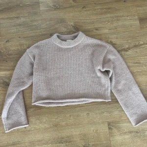 Ljusbeige/rosa lite croppad stickad tröja H&M - Supermjuk och fluffig ljusbeige/rosa stickad tröja från H&M med glittereffekt. Croppad modell med ribbad halsringning och långa ärmar. 