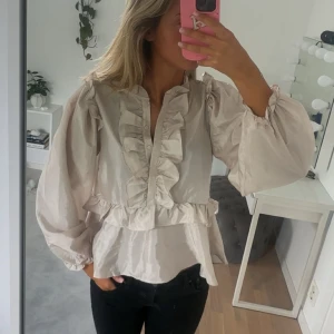 Blus - Säljer denna jättefina blus från Neo Noir! Med knappar framtill och fina volang detaljer. Blusen går även att justera till trekvartsärmad!💕