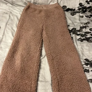 Bruna fleecebyxor med resårmidja - Supermysiga bruna fleecebyxor med bred resår i midjan där det står 'STAY COOL'. Byxorna har en loose passform och är perfekta för chill dagar hemma. Materialet är fluffigt och mjukt, vilket gör dem extra bekväma. Säljer som sett. 