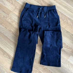 Mörkblå Juicy - Snygga mörkblå Juicybyxor med bred resår i midjan och snörning framtill. Byxorna har två stora fickor fram och två bakfickor med knapp. Sköna och mjuka, perfekta för chill dagar eller när du vill vara bekväm men ändå se fräsch ut.