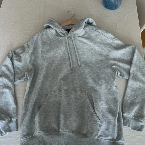 Grå hoodie från H&M loose fit XS - Säljer en grå hoodie från H&M i loose fit-modell, storlek XS. Tröjan har huva med snörning, magficka och ribbade muddar vid ärmslut och nederkant. Perfekt för chill dagar och enkel att matcha med jeans eller mjukisbyxor.