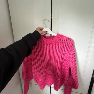 Stickad rosa tröja från H&M - Säljer en chunky stickad tröja från H&M i en riktigt poppig rosa färg. Tröjan har breda muddar, rund halsringning och lång ärm. Perfekt för dig som vill ha en färgklick i garderoben och gillar oversized känsla.