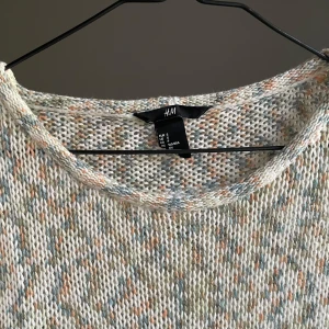 Stickad kortärmad tröja från H&M - Säljer en stickad kortärmad tröja från H&M i storlek S. Tröjan har en melerad look i ljusa toner av beige, blått och orange. Den är luftig och har rund halsringning, perfekt för vår och sommar. Passformen är normal och materialet känns mjukt mot huden.