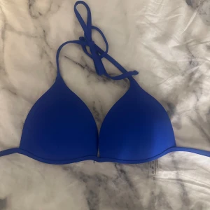 Blå trekantsbikini med knytband i strl XS - Snygg blå trekantsbikini med tunna knytband i nacken och ryggen. Bikinin är enkel och stilren utan mönster, med vita insidor och blå kant. Sömmen har typ gått upp lite på ena sidan av bandet men den funkar att använda och de är inget som märks när man använder den, har använt den max 3 gånger💗finns en underdel också i samma färg men tog ingen bild på den för tänkte att man kanske inte köper sånt begagnat💗underdelen ingår i priset ifall man skulle vilja ha den också💗