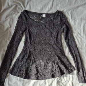 Svart spetsblus från H&M Divided XS - Supersnygg svart blus i spets från H&M Divided. Blusen har lång ärm, rundad halsringning och är helt täckt av blommig spets som ger en romantisk vibe. Perfekt att styla med jeans eller kjol för en cool look. Sprucken vid ärmen men har sytt hålet, kan skicka bild på det privat. Dock syns det knappt. 