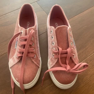 Rosa Superga sneakers i sammet - Snygga rosa Superga sneakers i sammet med vita, tjocka sulor och klassisk snörning. Skorna har låg profil och rund tå, perfekt för dig som vill ha en cool och trendig look. Superga-logga på sidan och bak på hälen.