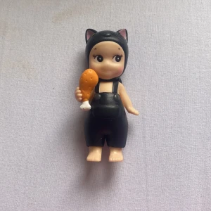 Sonny Angel - Svarta hängselbyxor i kort modell med breda axelband och hög midja. Byxorna har en cool kattsvans baktill och matchas med en kattmössa. Perfekt för dig som gillar unika och lekfulla plagg.