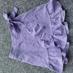 Ljuslila kjol med volang - Superfin ljuslila kortkjol med små vita detaljer och volang längs nederkanten. Kjolen knyts i sidan och har en flowy känsla, perfekt för en varm sommardag☀️💕Har använt den 1 gång och Kjolen är i strl Xs!