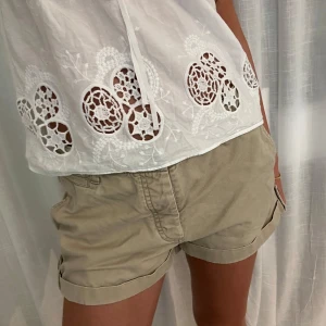 Beige shorts från NN.07 med knappar - Beiga shorts från NN.07. De har uppvikta benslut, knappar i sidorna och fickor både fram och bak. 