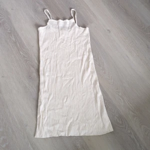Ribbad ljusbeige klänning från Zara - Supersöt ribbad klänning från Zara i ljusbeige med smala axelband och rak passform. Klänningen har ett diskret randigt mönster och är perfekt för varma dagar. Enkel och stilren design som är lätt att matcha med sneakers eller sandaler.