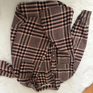 Rutig rosa och svart skjorta - Snygg skjorta i rosa och svart rutigt mönster med knappar framtill. Skjortan har klassisk krage och långa ärmar. Perfekt för dig som vill sticka ut lite extra med ett coolt mönster och trendiga färger.